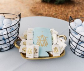 Wire baskets of golf balls and monogrammed favors on a round table—stylish inspiration for New Orleans weddings.