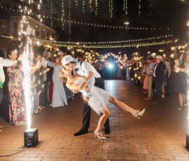 A couple kisses while dancing among sparklers and fireworks at a nighttime Louisiana wedding with cheering guests.