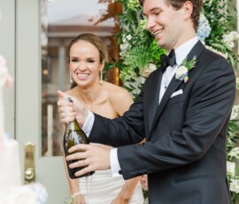 Bride and groom celebrate with champagne amid lush floral decor at their New Orleans wedding.