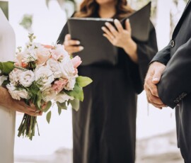 Bride with bouquet and groom stand together as officiant holds a book during a New Orleans wedding ceremony.