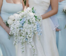 Bride in white with cascading white and blue bouquet stands with bridesmaids in light blue at an elegant Gulf South wedding.