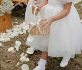 Young girl in white dress scatters rose petals from a basket at an outdoor New Orleans wedding.