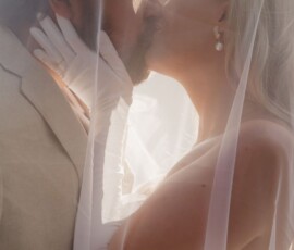 Bride and groom kiss under a sheer veil, sunlight on their faces, capturing timeless Louisiana wedding romance.