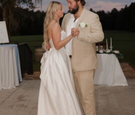 Bride and groom dance outdoors at sunset during their Louisiana wedding, with greenery and a decorated table behind them.