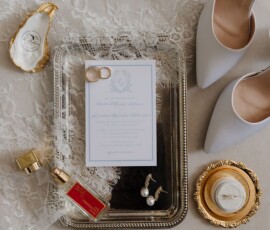 Wedding accessories flat lay: white heels, lace veil, pearl earrings, rings, ring box on a silver tray—New Orleans elegance.
