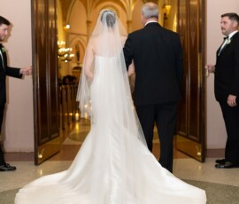 Bride in white gown with older man at open doors, ready to walk down the aisle at a New Orleans wedding ceremony.