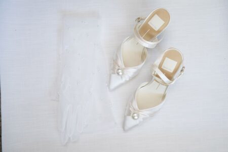 White bridal shoes with pearl accents and a beaded veil on a light background, ideal for a Louisiana wedding.