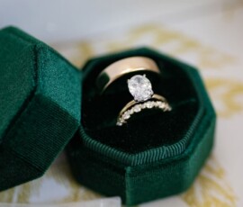 Gold band and diamond engagement ring with matching wedding band in a green velvet jewelry box.