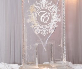 Elegant rectangular ice sculpture with ornate design and large letter C, displayed on white cloth—ideal for Louisiana weddings.