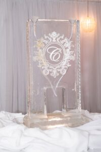 Elegant rectangular ice sculpture with ornate design and large letter C, displayed on white cloth—ideal for Louisiana weddings.