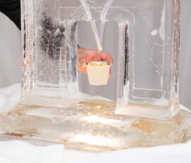 A hand collects liquid in a cup from an ice sculpture spout, a stylish detail popular at New Orleans weddings.