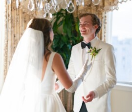 Bride and groom smile indoors under chandelier at their Louisiana wedding, sunlight streaming through window.
