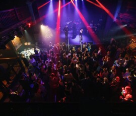 Crowd enjoys live music on stage with red and blue lights in a packed indoor venue, capturing vibrant Gulf South wedding energy.