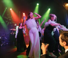 Formally dressed guests dance and celebrate under colorful lights, raising glasses—vibrant Louisiana wedding inspiration.