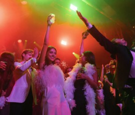 Guests in formalwear and feather boas celebrate under colorful lights at a lively Louisiana wedding reception.