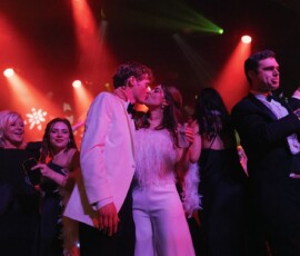 Couple kissing on a vibrant, crowded dance floor amid party lights and celebrating guests—Gulf South wedding inspiration.