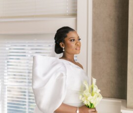 Bride in modern white wedding dress with dramatic sleeves, holding calla lilies by a window—New Orleans wedding inspiration.