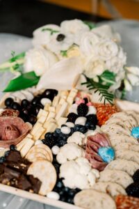 Charcuterie board with cheeses, meats, crackers, berries, and a white flower bouquet—ideal for a romantic New Orleans wedding.
