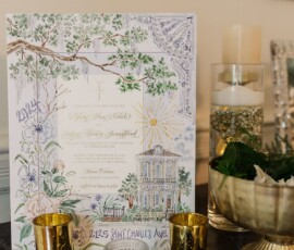 Elegant wedding invitation with gold candle holders, florals, and greenery on a dark surface for a New Orleans ceremony.