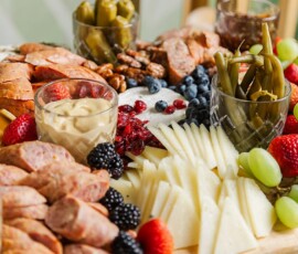 Charcuterie board with meats, cheeses, fruits, pickles, nuts, and mustard on wood—ideal for New Orleans wedding inspiration.