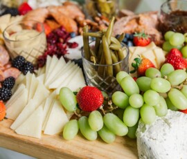Charcuterie board with grapes, berries, meats, cheese, pickled beans, and dips on a wooden tray—great for wedding receptions.