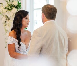 Bride and groom exchange vows indoors amid white floral decor at a classic New Orleans wedding ceremony.