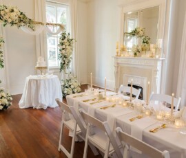 White and gold wedding setup with floral arch, cake table, and candlelit dining in a bright room—ideal Louisiana wedding inspo.