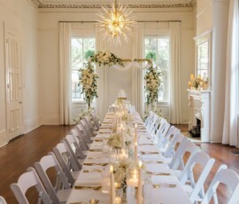 Chic New Orleans wedding reception with a long decorated table, floral centerpieces, candles, cake, and elegant lighting.
