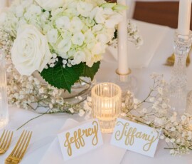 Sophisticated New Orleans wedding table with white flowers, candles, gold cutlery, and place cards for Jeffrey and Tiffany.