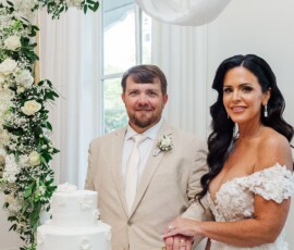 Bride and groom smile as they cut a white wedding cake at their elegant New Orleans reception, with floral and draped décor.