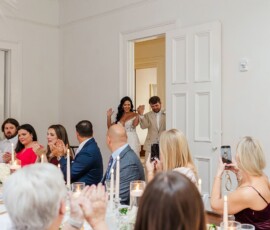 Bride and groom enter to cheering guests at a New Orleans wedding with elegant décor and candlelit tables.