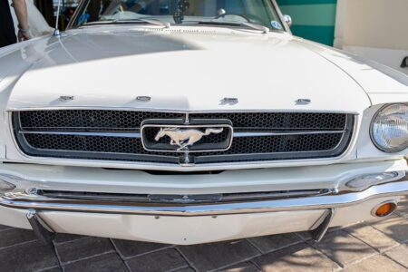 Classic white Ford Mustang front grille and emblem on stone pavement, ready for a New Orleans wedding reception.