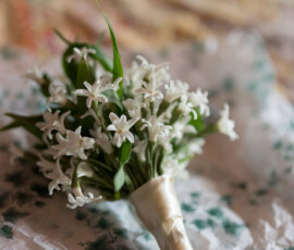 White flower bouquet with green leaves and ribbon on floral tissue paper, ideal for a romantic New Orleans Columns Hotel wedding.