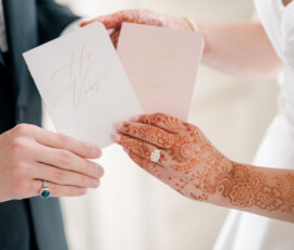Bride and groom hold matching vow books at their Indian wedding, highlighting henna and rings at The Ritz-Carlton New Orleans.