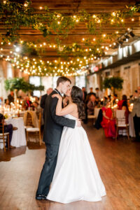 Bride and groom share their first dance at a Louisiana wedding, surrounded by guests, greenery, and string lights.