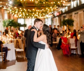 Bride and groom share their first dance at a Louisiana wedding, surrounded by guests, greenery, and string lights.