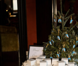 A small Christmas tree and white favor boxes decorate a round table at The Columns Hotel New Orleans wedding.