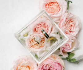 Elegant diamond and gold rings in a clear box, with pink roses, evoke an Indian wedding at The Ritz-Carlton New Orleans.