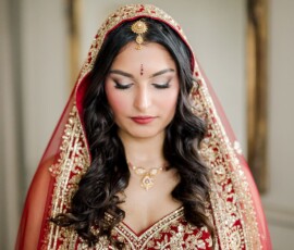 Woman in red and gold embroidered outfit with veil, jewelry, and wavy dark hair—ideal Louisiana wedding inspiration.
