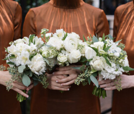 Three people in copper dresses hold white flower bouquets at a New Orleans wedding at The Columns Hotel.