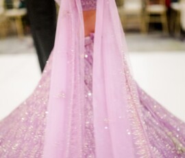 Woman in a sparkly lavender outfit dances with outstretched arm at a lively New Orleans wedding; blurred guests and lights behind.