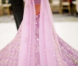 Close-up motion shot of a bride twirling in a sparkling lavender lehenga, her outstretched arm showing henna and matching bangles as the skirt swirls across the dance floor.