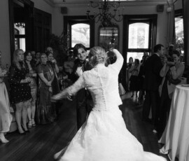 Bride and groom dance at The Columns Hotel, surrounded by smiling guests and elegant décor. Black and white New Orleans wedding.
