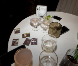 Round table with empty glasses, instant camera, photos, phone, and candle holder at New Orleans second line wedding.