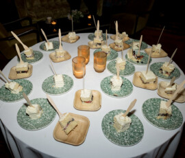 Round table set with cake slices on green and white plates, wooden trays, and three lit candles for a New Orleans wedding vibe.