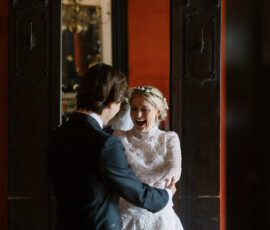 Bride and groom embrace and smile by a large mirror in an elegant, warmly lit Columns Hotel New Orleans wedding.
