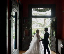 Bride and groom hold hands in a bright doorway, framed by greenery at New Orleans’ Columns Hotel wedding.