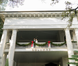 Couple on a balcony with garland and red bows at The Columns Hotel, New Orleans wedding venue.