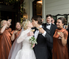 Bride and groom kiss with champagne as wedding guests in copper dresses and black suits raise glasses at New Orleans ceremony.