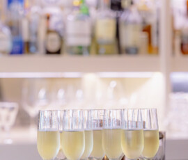 Champagne flutes on a silver tray at a bar, perfect for Gulf South weddings, with blurred bottles in the background.